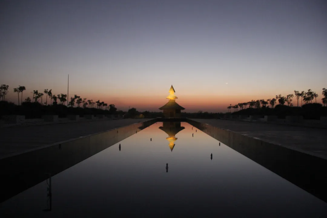 The temple at dusk, at the end of a long still pool, its reflection in the water