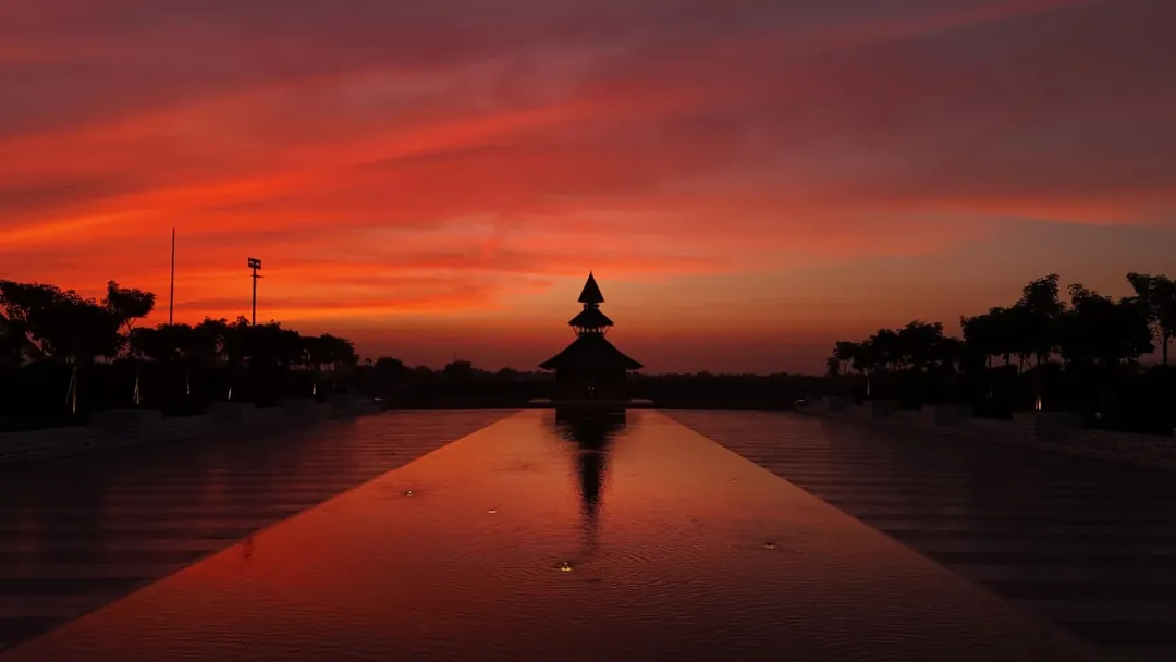 The temple silhouetted under a red sky, mirrored in the pool